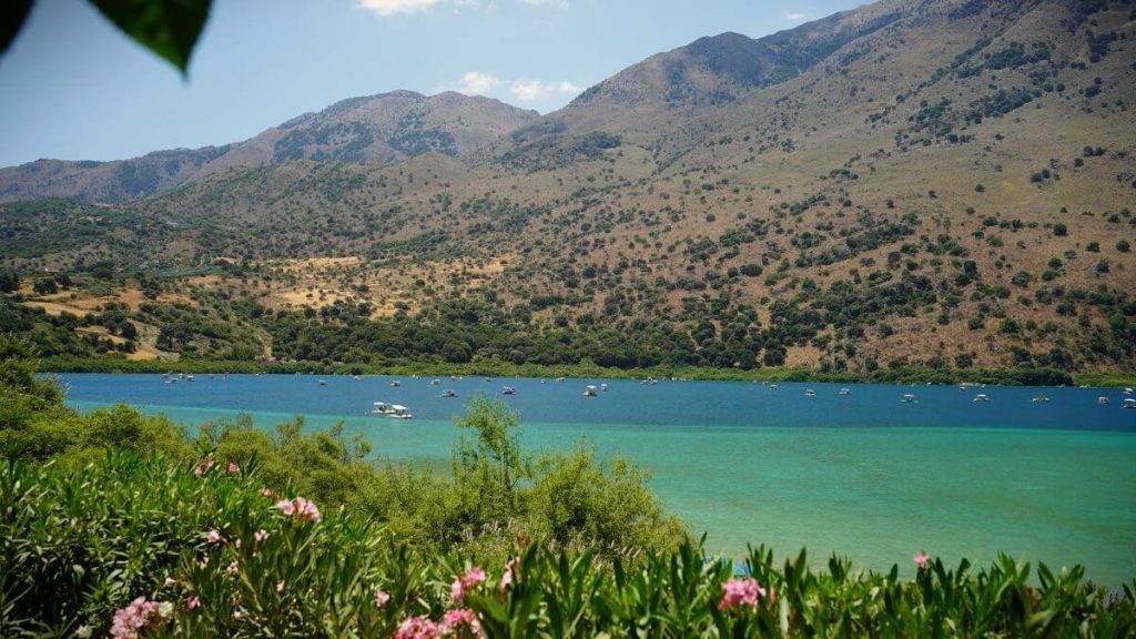 Lago di Kournas, Creta. Panorama lago azzurro, montagne e pedalò.