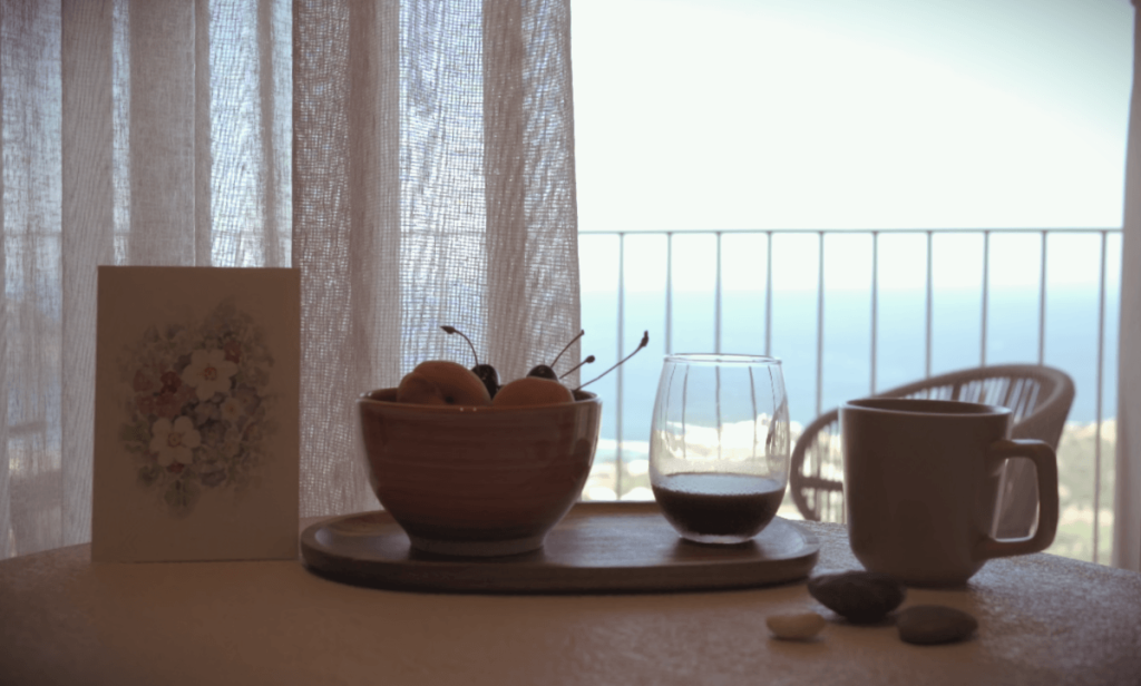 Tavolo con tazza frutta e caffè, in una mattina a Creta con vista mare blu