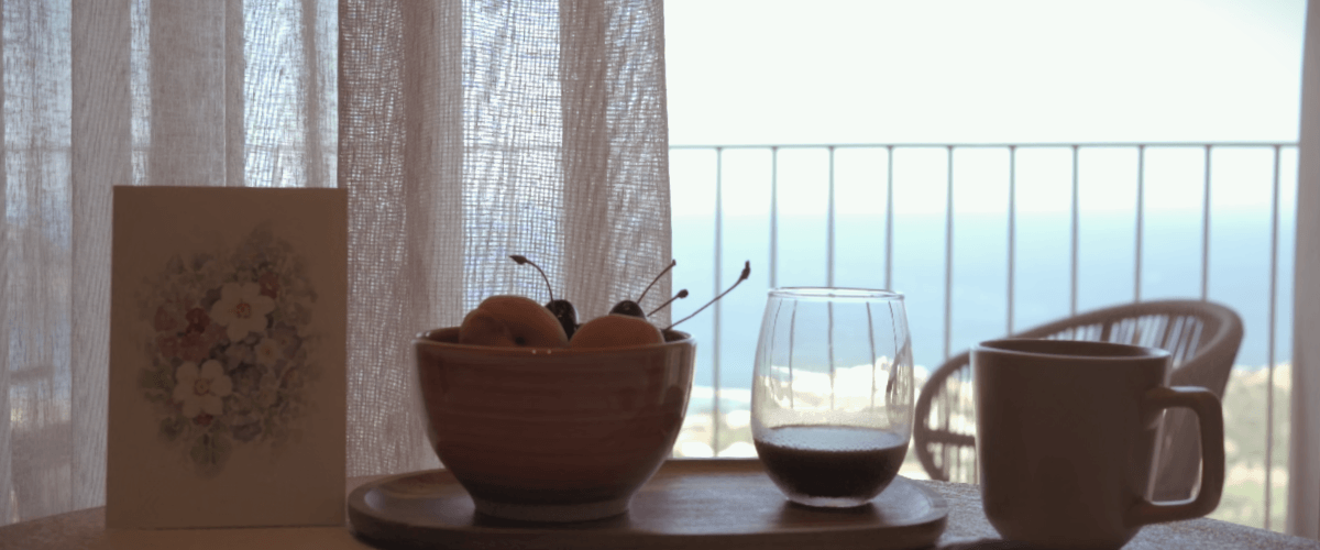 Tavolo con tazza frutta e caffè, in una mattina a Creta con vista mare blu