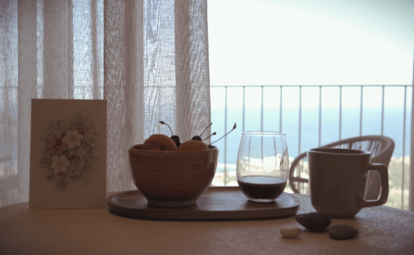 Tavolo con tazza frutta e caffè, in una mattina a Creta con vista mare blu
