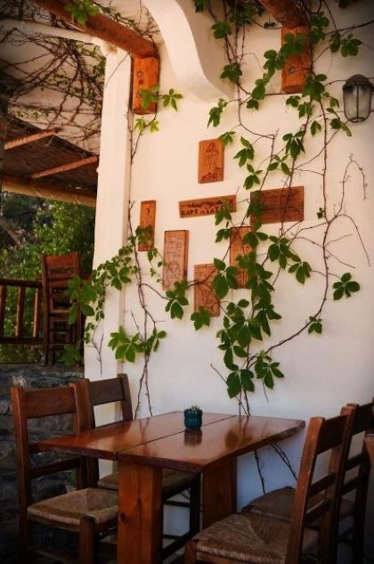 Una taverna tipica con tavolino e sedie in legno e piante rampicanti al villaggio di Spili, Creta