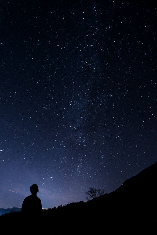 Persona in meditazione davanti a un cielo stellato