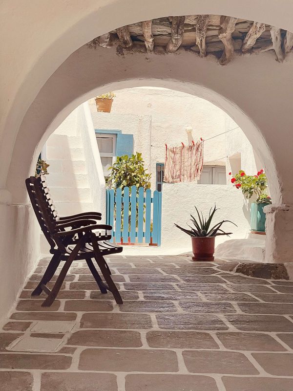 Slow living, piccolo cortile mediterraneo con arco in pietra, sedia e piante