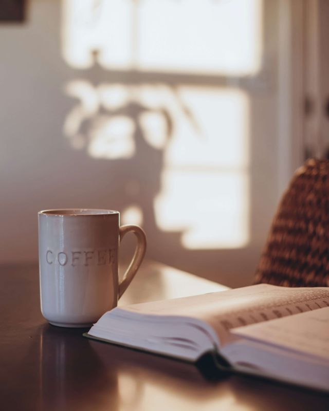 Vita lenta, tazza di caffè e libro aperto alla luce del mattino