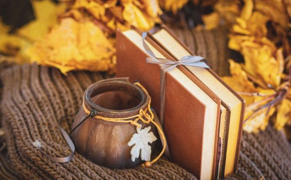 Libri e foglie autunnali su una coperta intrecciata