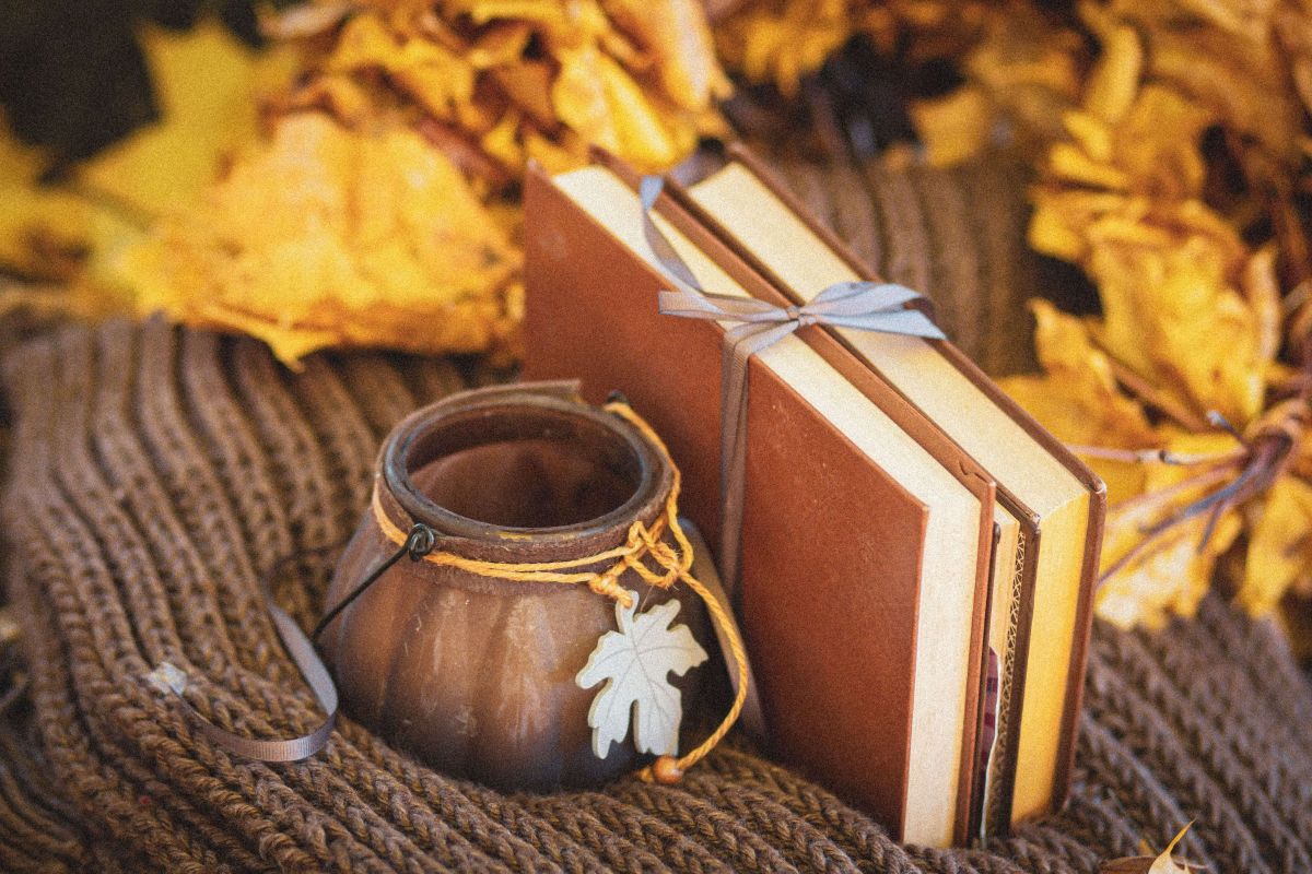 Libri e foglie autunnali su una coperta intrecciata